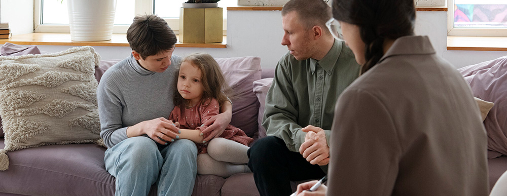Eltern mit Kind in Beratungsgespräch bei Fachperson – rechtliche Unterstützung in familiären Konflikten durch Familienrechtsschutz.